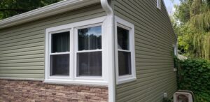 White double-hung windows on a suburban home with beige siding and stone veneer